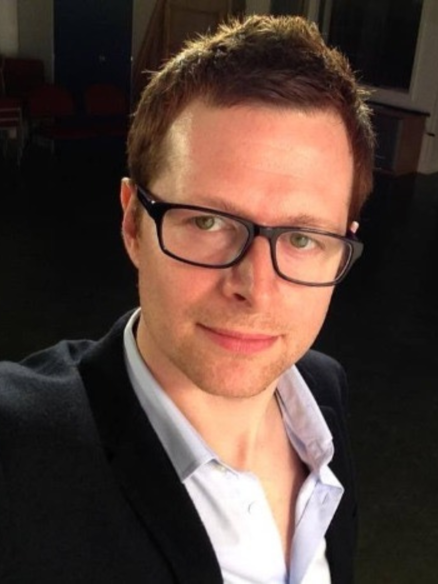 Alex Canner wearing a dark suit and glasses