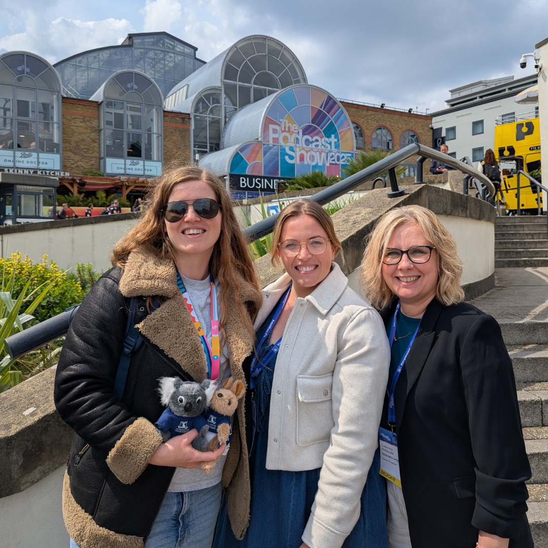 Krissie Brighty-Glover, Lauren White and Catherine McDonald at the Podcast Show 2025 stood infront of the main building smiling