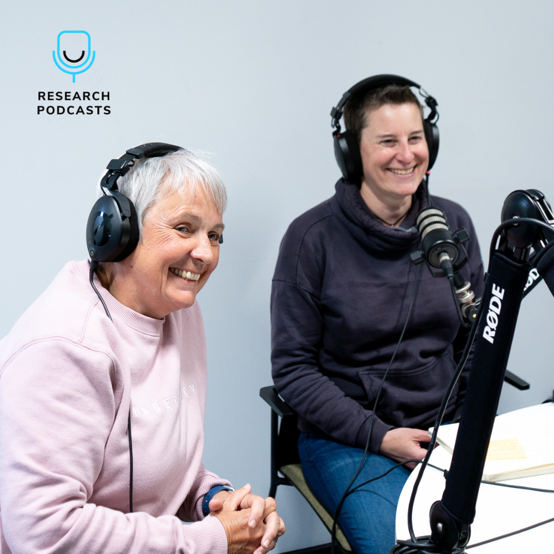 Chris Garrington and Izzy Bartley smiling in a recording booth with headphones on and Rode Mics